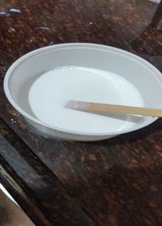 A white bowl with a wooden stick in it

Description automatically generated